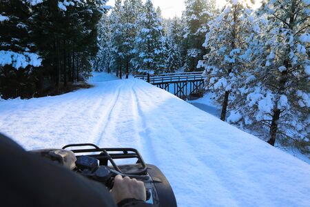 Man riding snowmobile or fourwheeler on the country side trail near water canal.の写真素材