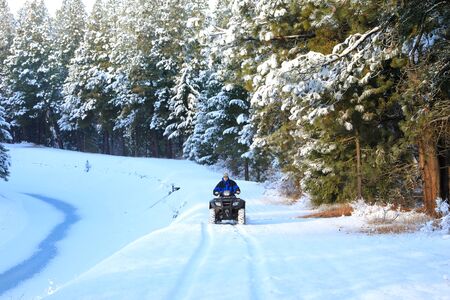Man riding snowmobile or fourwheeler on the country side trail near water canal.の写真素材