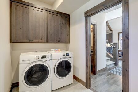Laundry room with white wahser and dryer and dark brown wood cabinets.の写真素材