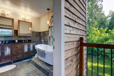 Bathroom interior with grey tiles and free standing white tub with open door to the balcony.の写真素材