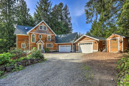 Wooden large American house with natural brown tone with white trim and green summer nature with double garage.の写真素材