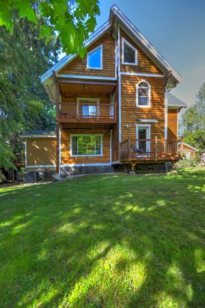 Wooden large American house with natural brown tone with white trim and green summer nature.の写真素材