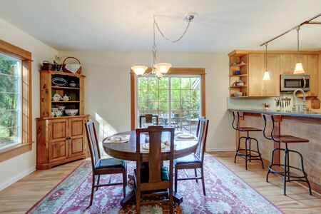Nice country home wood kitchen with wooden island and ligth green tiles with dining room  dark cherry round table.の写真素材