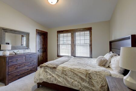 Bedroom interior with beige walls and wood trim and natural tone bedding.の写真素材