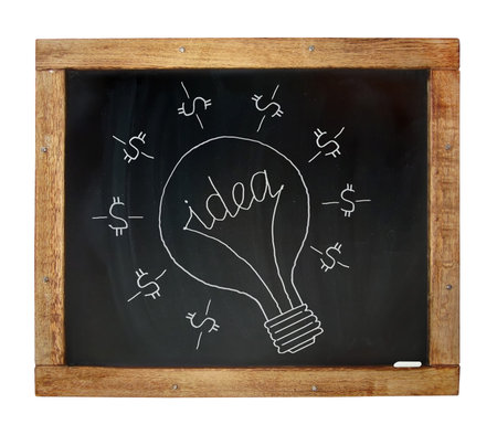 There is a chalk drawn dollar light bulb with a word idea instead of a spiral on a blackboard. White...
