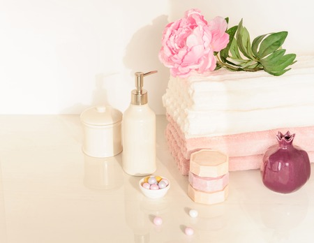 Bath setting in white and pink colors. Towel, aroma oil, flowers, soap. Selective focus, horizontal.の写真素材