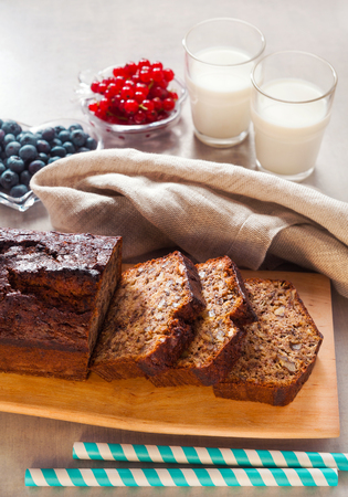 sliced banana bread with two glasses of hot milk and fresh berriesの写真素材