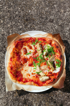 whole pizza in plate on natural stone with artichoke and arugula . の写真素材