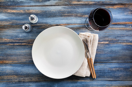 empty plate on a wooden background of old shabby boards and glass of red wine . background for billboards, web site , use in advertising, for restaurants and cafes の写真素材