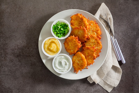 Potato pancakes, latkes or boxty and sauces from sour cream, yogurt, apple sauce and finely chopped green onion on grey stone backgroundの写真素材