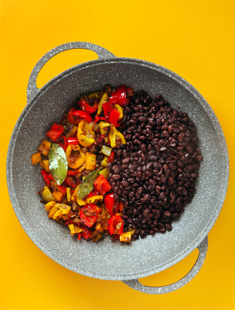 cooking a Mexican spicy dish with a wide frying pan. a dish of black beans. healthy vegetarian vegan cuisine without glutenの写真素材