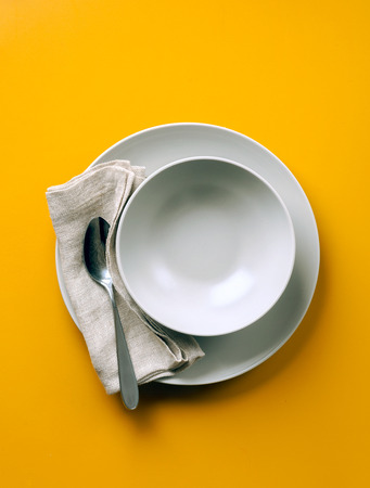 empty plate for soup on a yellow backgroundの写真素材