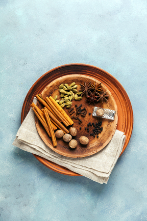 Spice collection on the plate : cinnamon sticks, nutmeg, anise, cardamom, black pepper, cloves. on blue table background. の写真素材