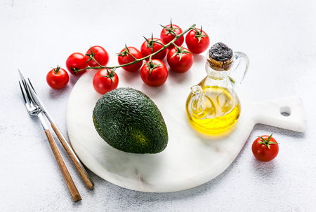 ingredients for guacamole on a marble board. Avocado and tomatoes with olive oil are ready to be used for a recipeの写真素材