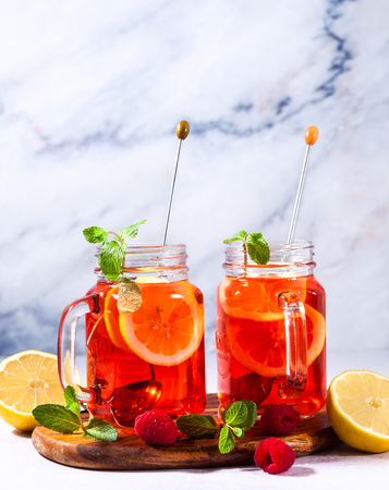 Iced tea with orange and raspberry in two glasses and mint の写真素材