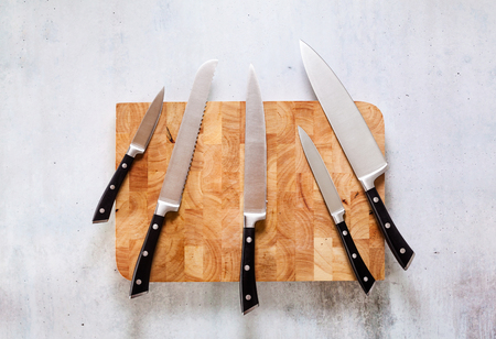 set of new professional kitchen knives on a wooden cutting board の写真素材