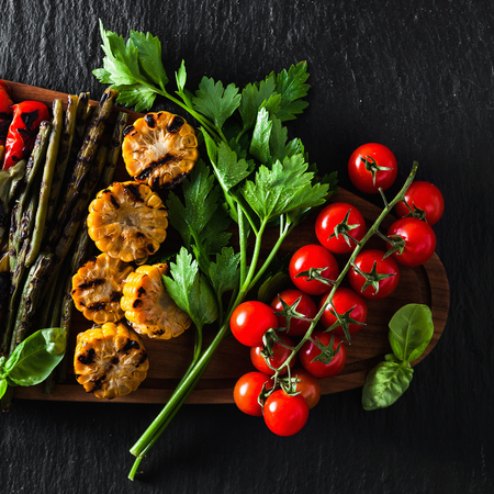grilled vegetables on a wooden tray on a black slate. copy space, overhead shotの写真素材