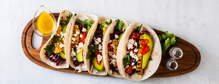 Vegetarian snack tacos with grilled vegetables, avocado, feta cheese, salad with small sweet peppers and sauce with lemon and olive oil. food background bannerの写真素材