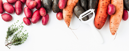 Different varieties in form and color of potatoes  on a white isolated background. red, Shetland Black potato and sweetの写真素材