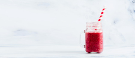 red natural berry smoothie in a glass jar with a handle. healthy eating, banner with copy spaceの写真素材