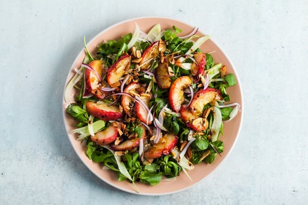 summer, very tasty salad with peaches, sweet onions and arugula with almonds on a table in a plate. simple healthy recipeの写真素材