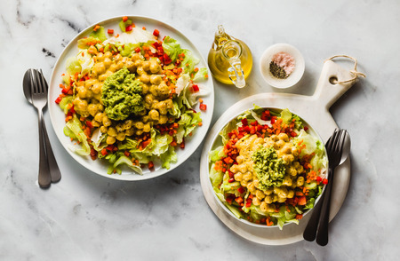 Healthy vegan salad with fresh vegetables, sprouts, avocados and chickpeas in mango juice. Raw food for a healthy familyの写真素材