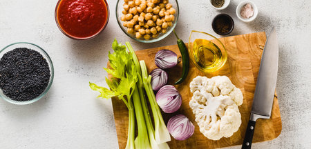 banner of ingredients for cooking soup on a cutting board on a white stone kitchen table.