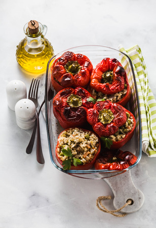 ready baked stuffed peppers in a glass baking dish on white marble table. healthy vegan cuisine for the whole family. comfort foodの写真素材