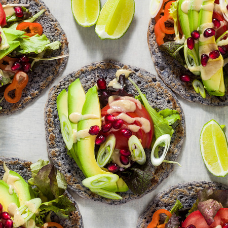 Gluten-free vegan tacos from black bean  with tomato and avocado salad  with tahini sauce and pomegranate seeds. healthy fast food for the whole family or partyの写真素材