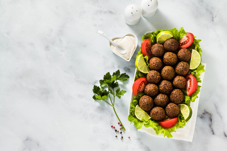 vegan falafel with cashew cheese sauce on a table with chopped tomatoes and lime slices. healthy food for the whole family or partyの写真素材