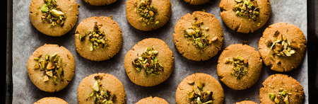 banner of homemade cookies, almond and sesame biscuits with pistachios. healthy vegan gluten free pastries on a baking trayの写真素材