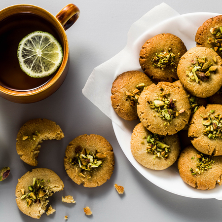 homemade cookies, almond and sesame biscuits with pistachios. healthy vegan gluten free pastries on the table with a kettle with green tea and cups. tea partyの写真素材