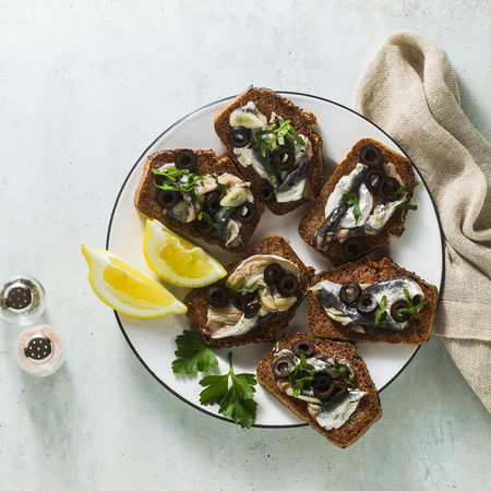 sandwiches with sardines marinated in olive oil with garlic and rye bread. summer light italian appetizer with lemon and parsleyの写真素材