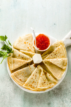 Traditional Russian pancakes with red caviar and butter on the white tableの写真素材