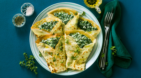 banner of Traditional Italian pancakes crepes with spinach and ricotta on a served blue table. healthy vegetarian dietの写真素材