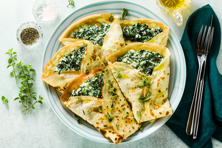 Traditional Italian pancakes crepes with spinach and ricotta on a served table. healthy vegetarian dietの写真素材