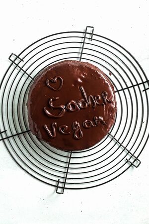vegan festive chocolate sacher cake with apricot jam on the table. written by chocolateの写真素材