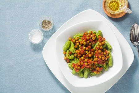 Italian fresh traditional sardinian pasta gnocchi with spinach and green pea tomato sauce. spring pasta for easter holidays.の写真素材
