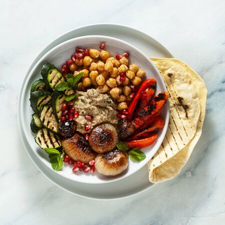 Italian Mediterranean Buddha bowl with Baba ghanoush caramelized onions, spicy chickpeas and grilled vegetables. healthy vegan food and pita breadの写真素材