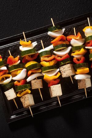 vegan kebabs of vegetables and smoked tofu, in a baking sheet, ready for baking in the ovenの写真素材