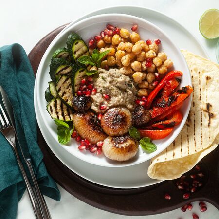 Italian Mediterranean Buddha bowl with Baba ghanoush caramelized onions, spicy chickpeas and grilled vegetables. healthy vegan food and pita breadの写真素材
