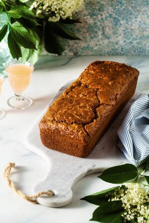 summer sweet loaf cake on a table with flowers and a drink in glasses. dessert for brunch or morning breakfastの写真素材