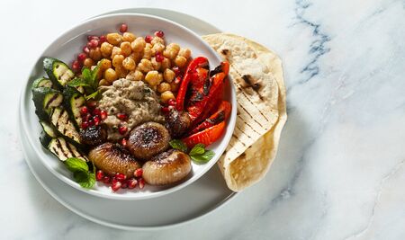 Italian Mediterranean Buddha bowl with Baba ghanoush caramelized onions, spicy chickpeas and grilled vegetables. healthy vegan food and pita breadの写真素材