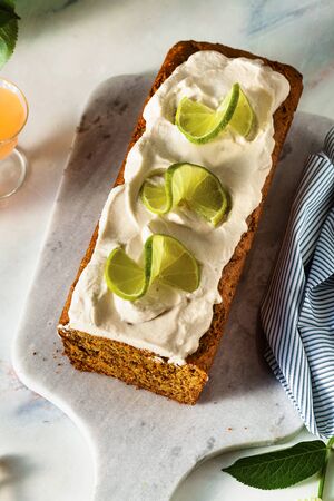 summer sweet loaf cake on a table with flowers and a drink in glasses. with coconut cream and lime. dessert for brunch or morning breakfastの写真素材
