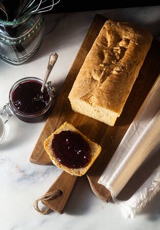 Fresh homemade sandwich bread and jam in a jar on the kitchen table, dark background.の写真素材
