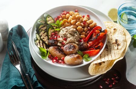 Italian Mediterranean Buddha bowl with Baba ghanoush caramelized onions, spicy chickpeas and grilled vegetables. healthy vegan food and pita breadの写真素材