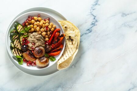 Italian Mediterranean Buddha bowl with Baba ghanoush caramelized onions, spicy chickpeas and grilled vegetables. healthy vegan food and pita breadの写真素材