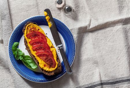 a sandwich with baked pumpkin hummus and tomatoes on a plate and a linen tablecloth. healthy snackの写真素材