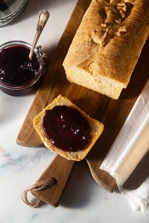 Fresh homemade sandwich bread and jam in a jar on the kitchen table, dark background.の写真素材