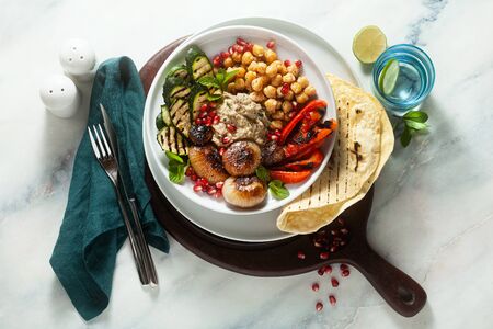 Italian Mediterranean Buddha bowl with Baba ghanoush caramelized onions, spicy chickpeas and grilled vegetables. healthy vegan food and pita breadの写真素材